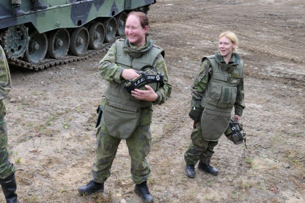 Kaksi naista maastopuvuissa panssariajoneuvon lähellä