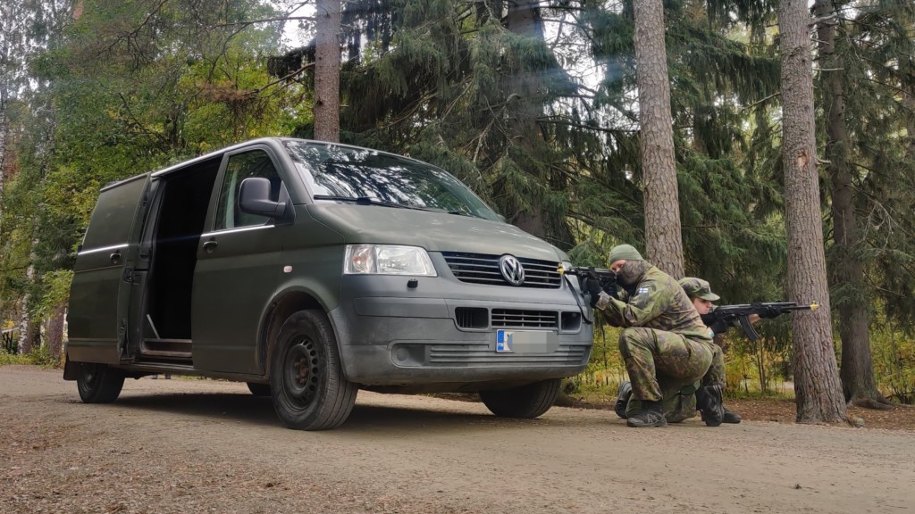 Kyykistyneet sotilaspoliisit puolustavat pakettiautoa