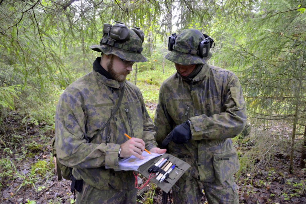 Kaksi miestä maastopuvuissa metsässä katsoo karttaa
