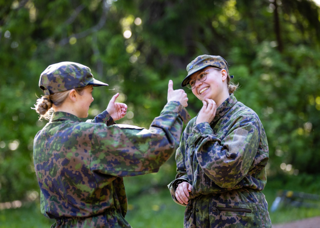 Kaksi naista metsässä maastopuvuissa harjoittelee voimankäyttöä