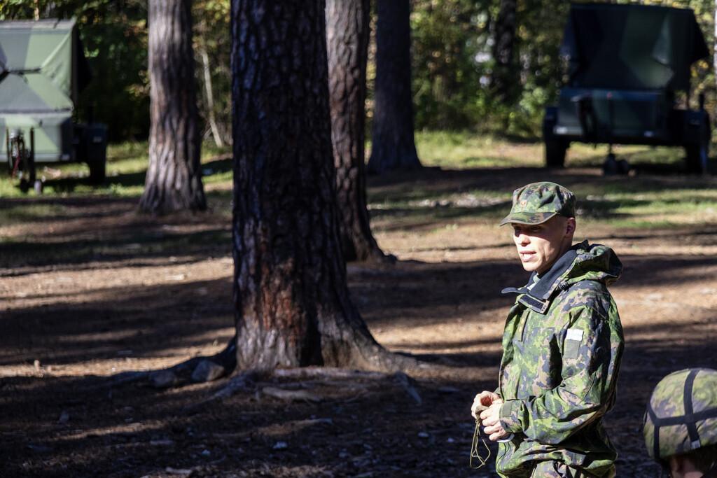 Puolustusvoimien asepuvussa oleva luutnantti puhuu metsäaukion edessä.