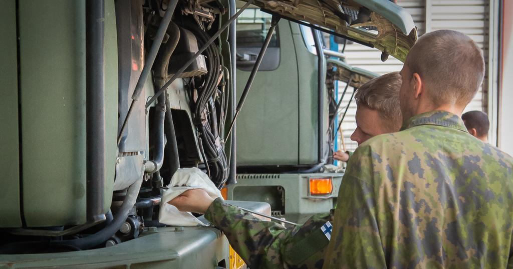 Kaksi henkilöä korjaamassa ison ajoneuvon moottoria.