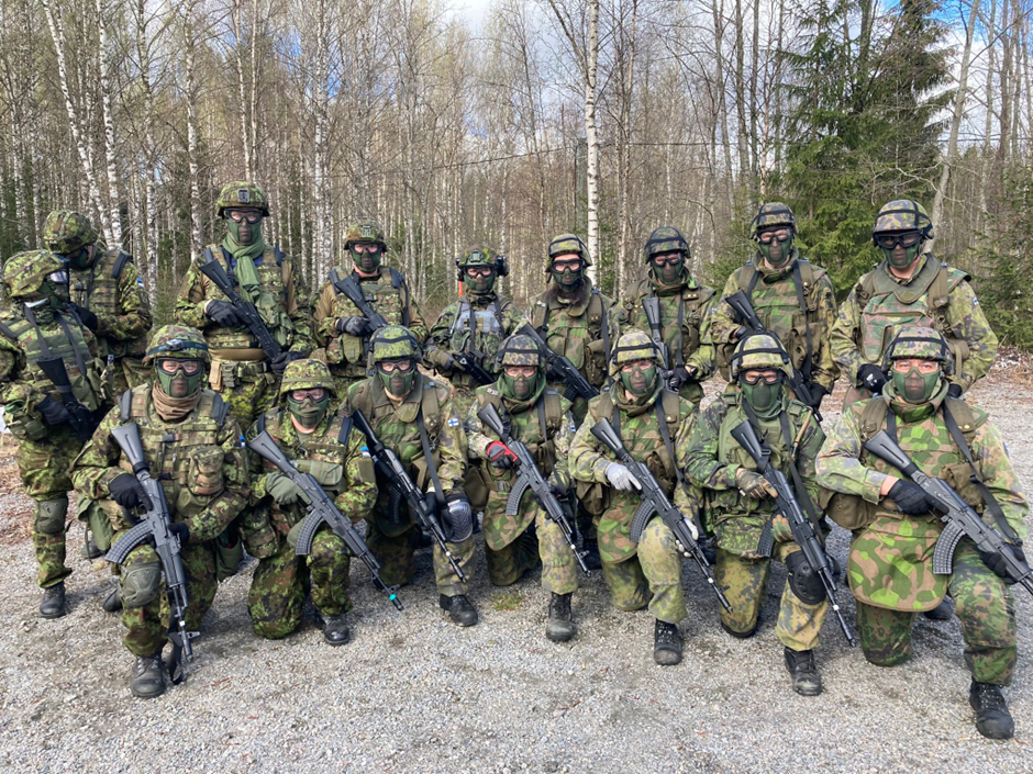 Maastopuvussa olevia sotilaita ryhmäkuvassa ulkona.