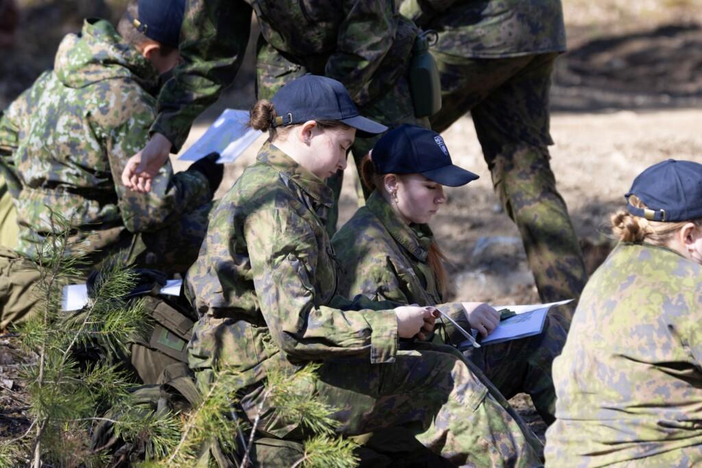 Nuoret metsässä tutkivat suunnistuskarttaa ja kompassia
