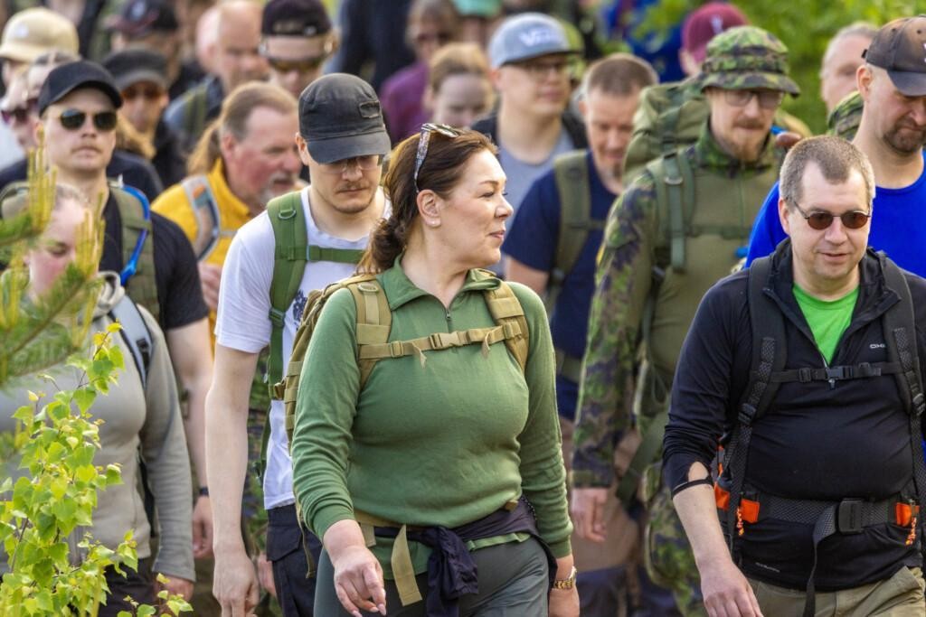 Paljon ihmisiä marssimassa metsäpolulla.