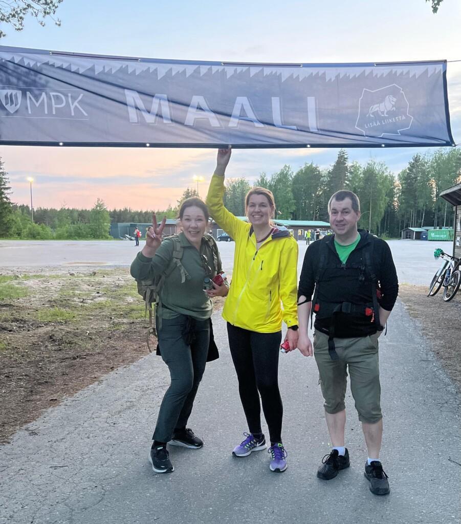 Kaksi naista ja yksi mies saapunut maaliin marssilta, onnellisesti hymyillen.