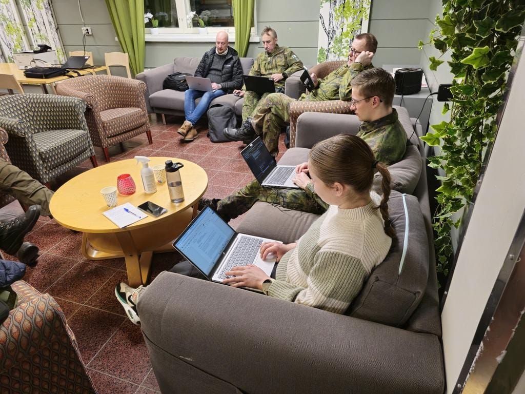 Viisi henkilöä työskentelemässä kannettavien tietokoneiden kanssa sohvaryhmällä, kukin omalla sohvallaan.