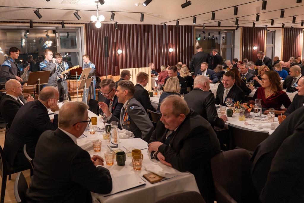 Juhlijoita vuosijuhlassa, varusmiesbändi soittamassa juhlijoille