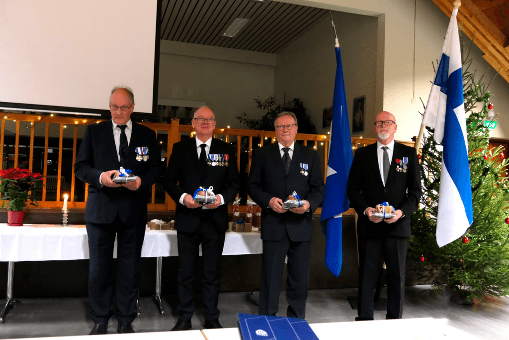 Ihmisiä juhlapuvuissa rivissä palkitsemistilaisuudessa.