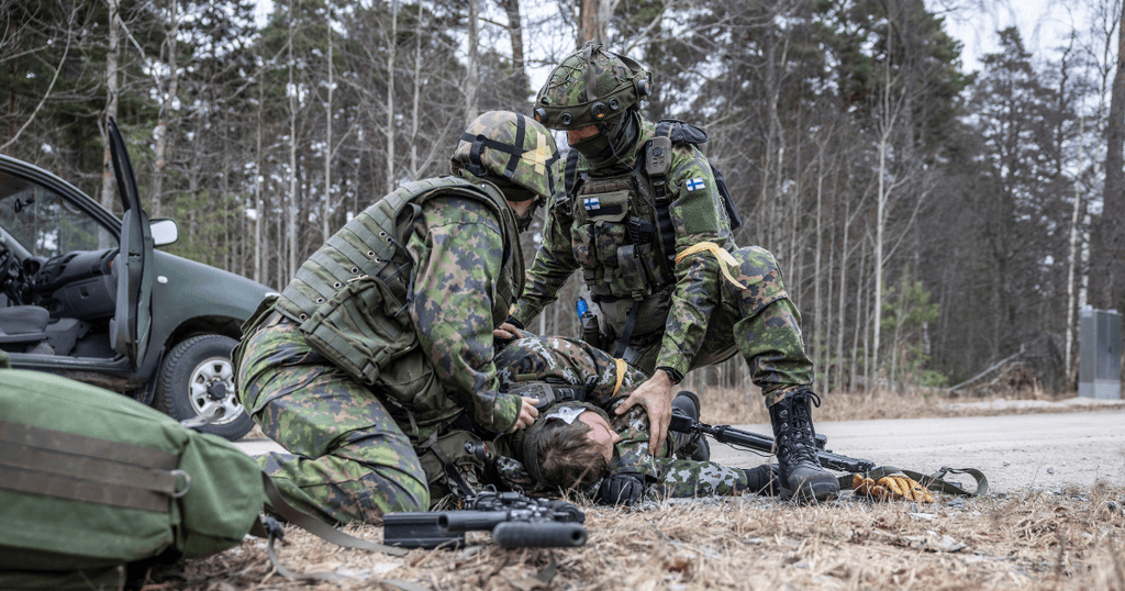 Kaksi sotilasta hoitaa kolmatta kenttälääkinnän harjoituksessa