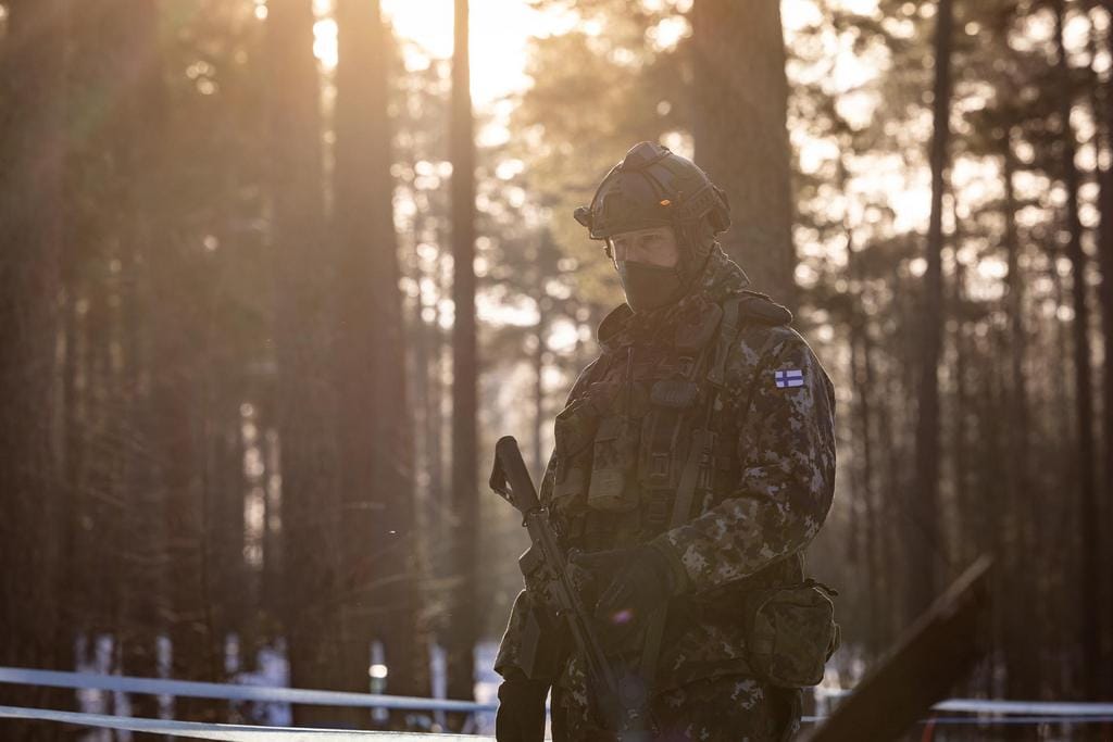 Sotilas aseen kanssa metsässä