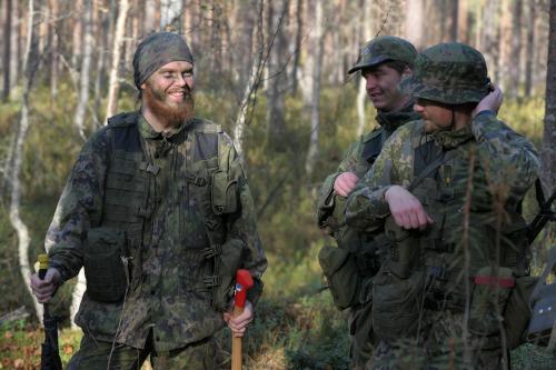 Kuvassa maastopukuisia henkilöitä metsässä.