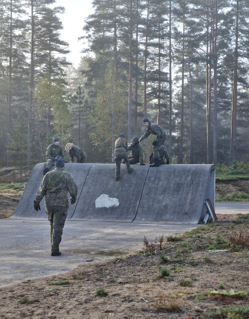 Ryhmä maastopukuisia henkilöitä ylittää estettä