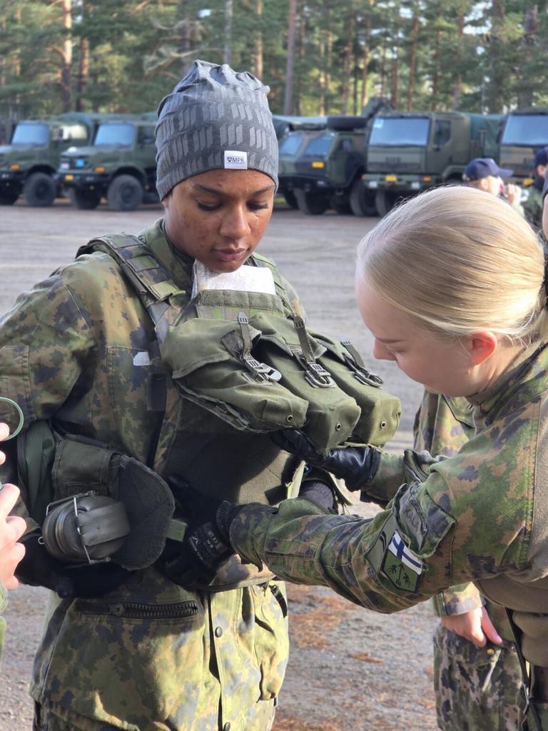 Kaksi tyttöä maastopuvuissa korjaa toisen reppua