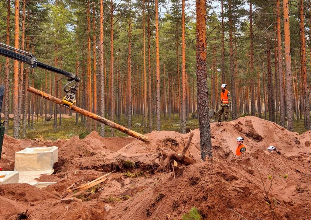 Nosturi ja ihmisiä metsässä hiekkakuopalla