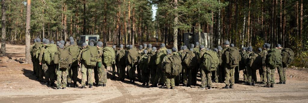 Ryhmä nuoria isot reput selässään metsän laidalla
