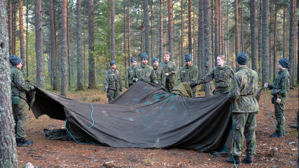 Ryhmä nuoria pystyttää suurta telttaa