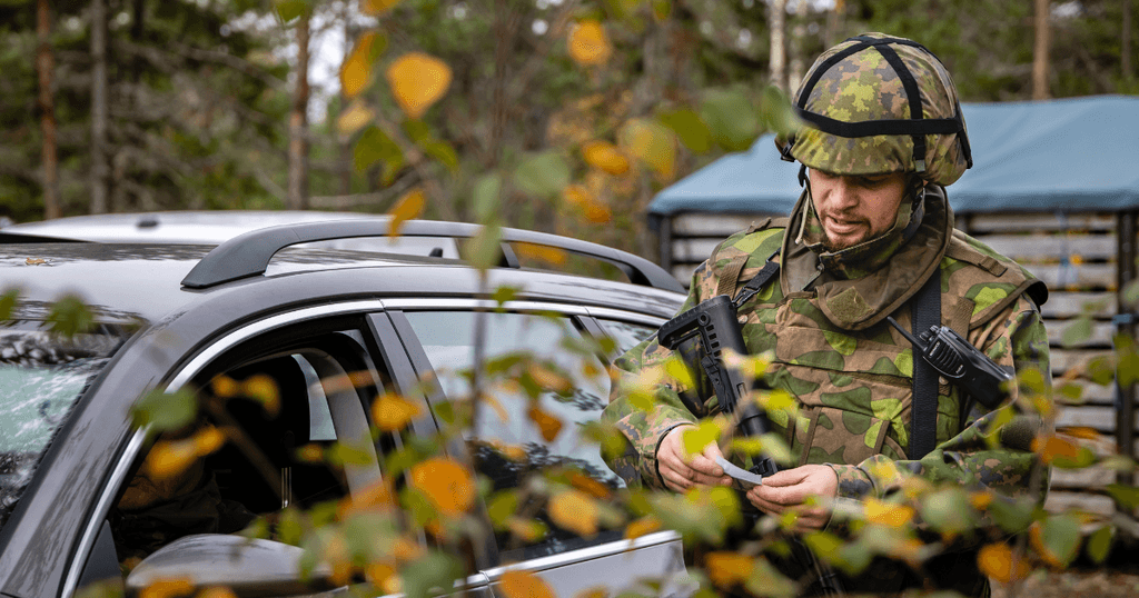 Sotilaspoliisi tarkastaa autoa syksyisessä metsässä
