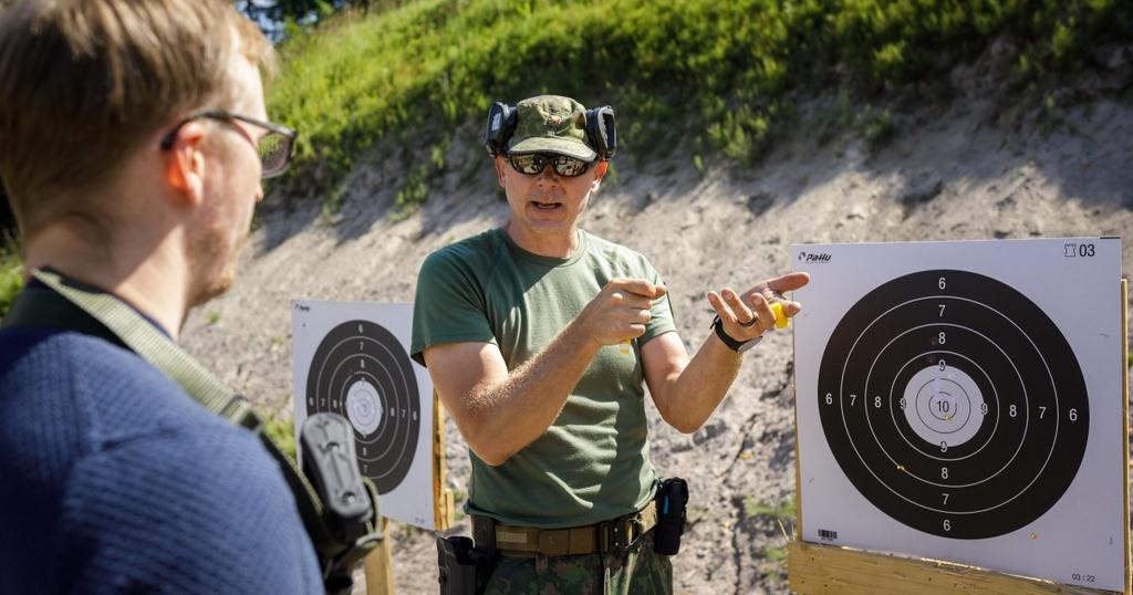 Sotilasasuinen ja siviiliasuinen henkilö ampumataululla.