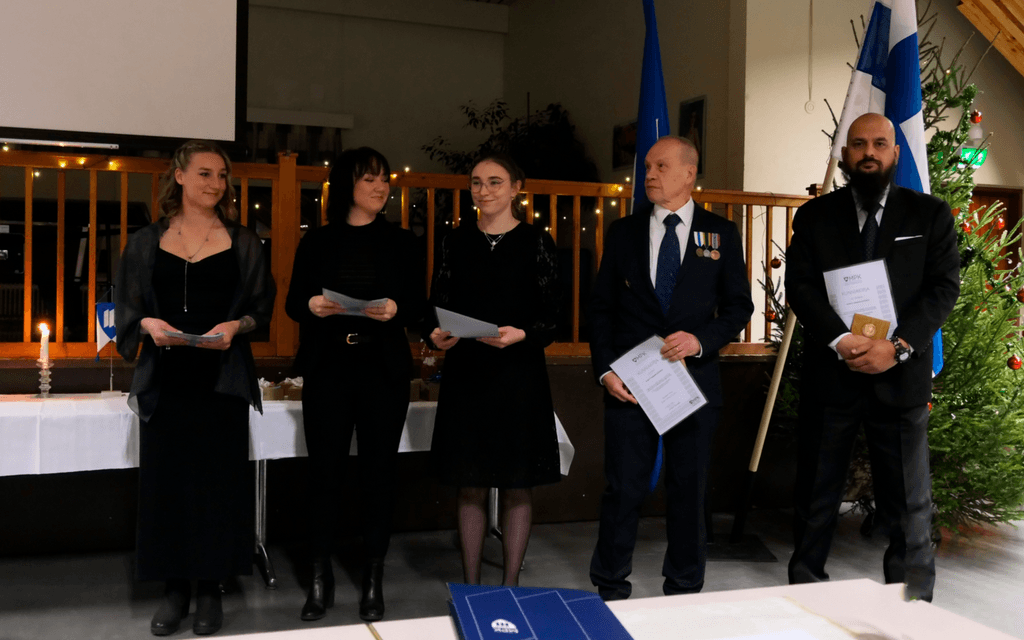 Ihmisiä juhlapuvuissa rivissä palkitsemistilaisuudessa.