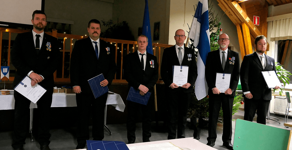 Ihmisiä juhlapuvuissa rivissä palkitsemistilaisuudessa.