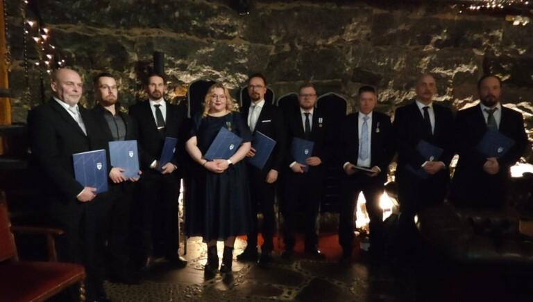 Ihmisiä juhlapuvuissa rivissä