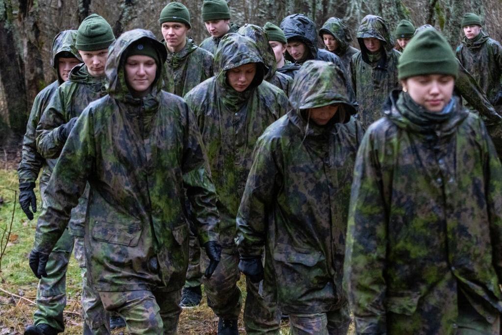 Nuoria maastopuvuissa ja maastokuvioinen sadevarustus päällä ulkona sateessa