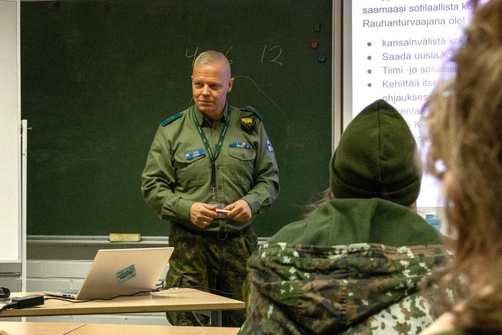 Mies sotilasasussa pitämässä luentoa nuorille.