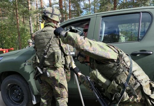 Maastopukuinen henkilö tarkistaa autoa