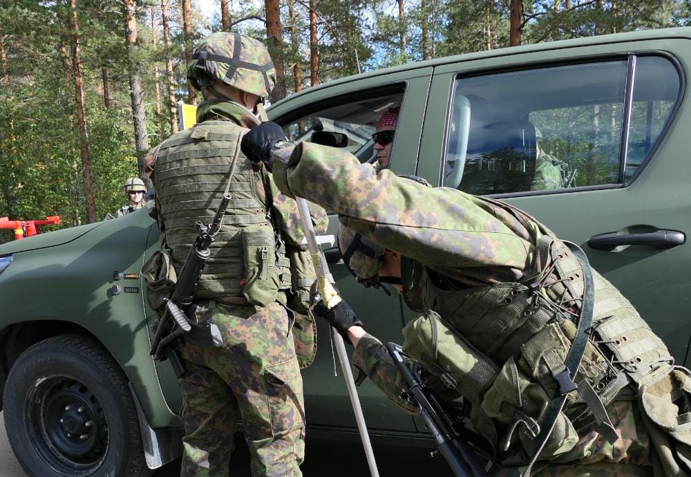 Maastopukuinen henkilö tarkistaa autoa