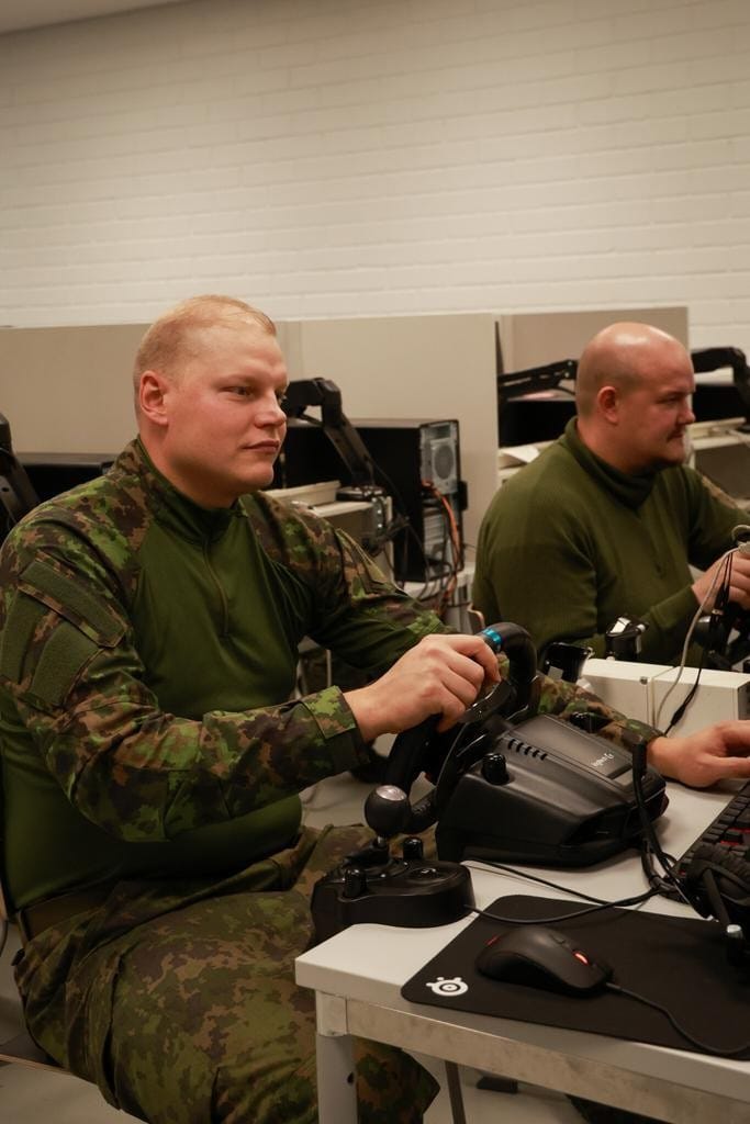 kaksi maastopukuista miestä istuvat tietokoneen ääressä.