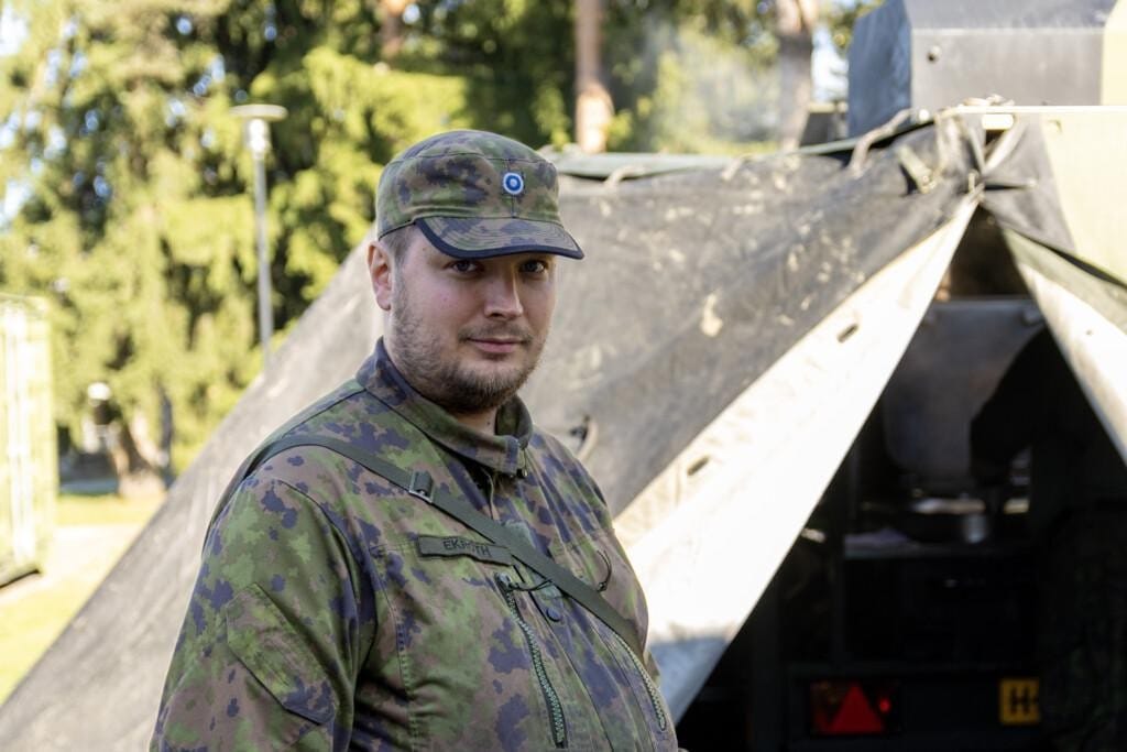 Sotilasasuinen mies teltan edessä