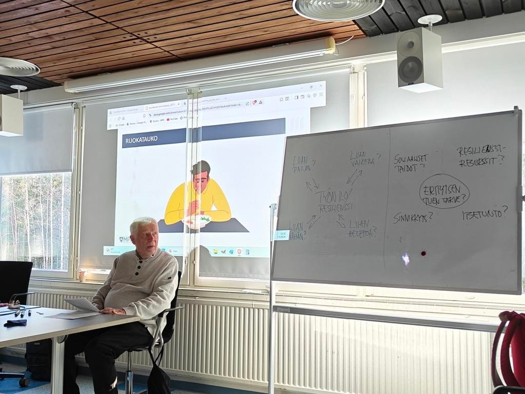 Mies istuu luokan edessä kertomassa resilienssistä.