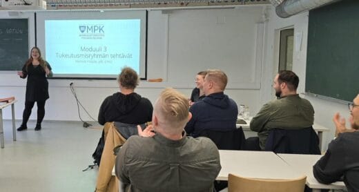 Kuva luokkahuoneesta. Nainen luennoi