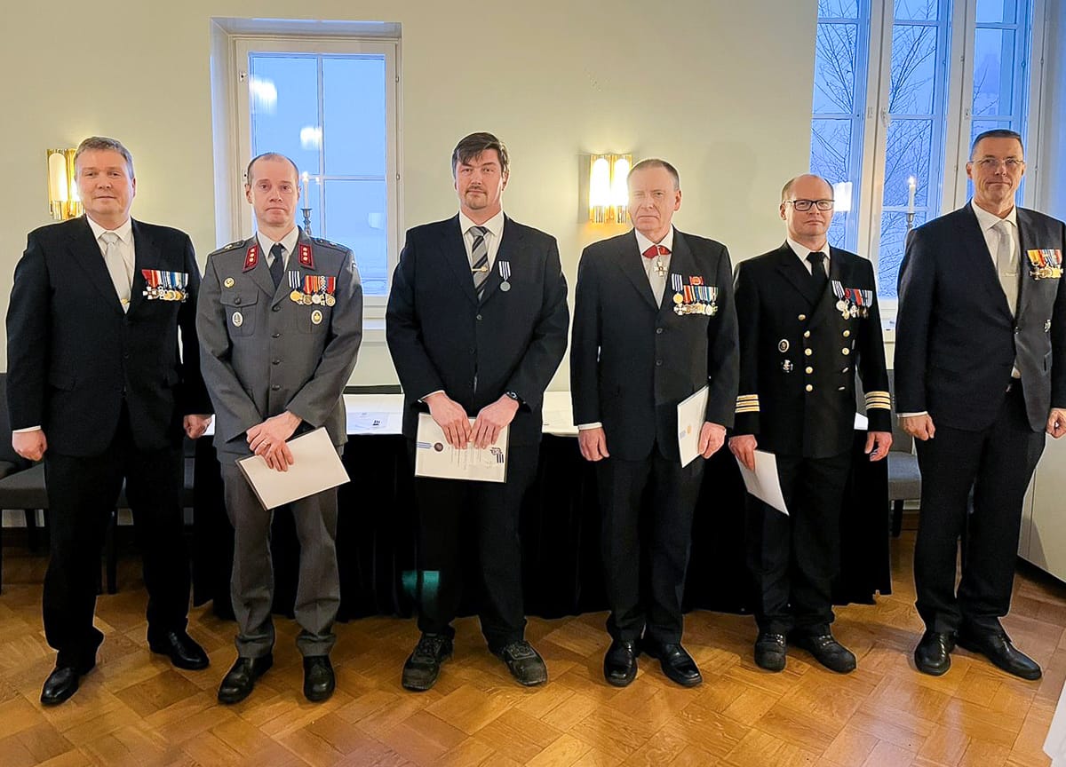 Juhla-asuiset MPK:n ansiomitalin saajat rivissä.