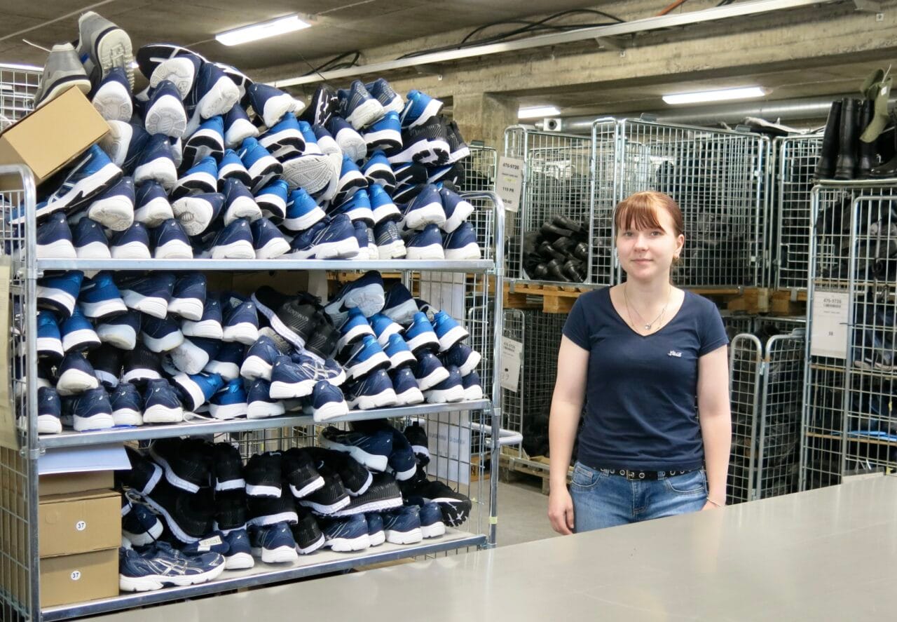 Nuori nainen seisoo varastossa kenkärullakon vieressä