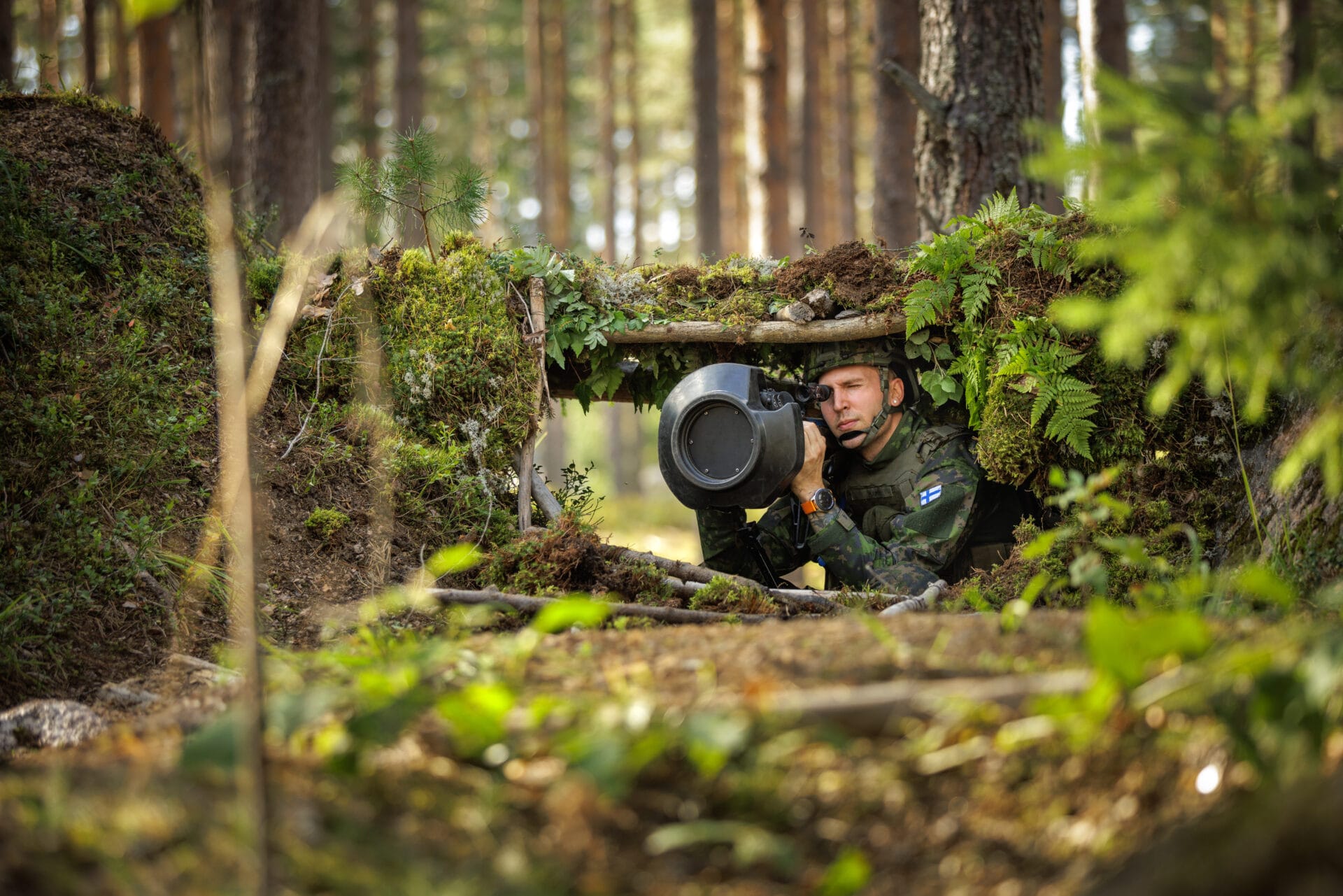 Sotilaspukuinen henkilö laavun alla panssaritorjunnassa