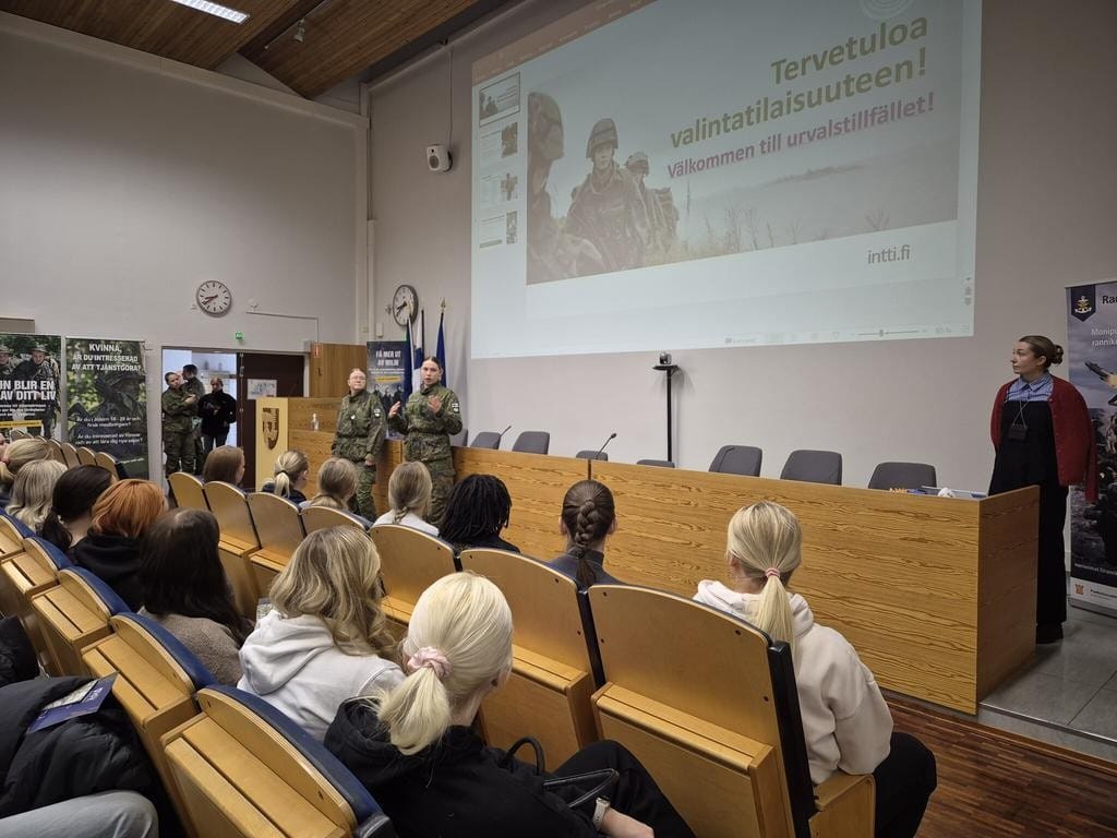 Nuoria auditoriossa kuuntelemassa esitelmää.