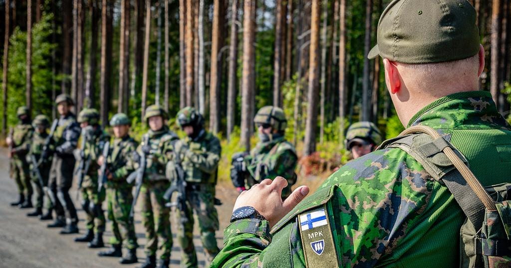 Maastopukuinen henkilö, jonka hihassa on MPK:n tunnus kouluttaa kouluttajia.