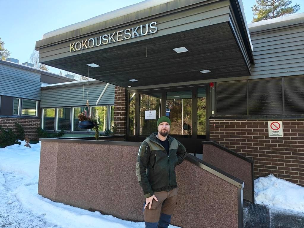 Mies seisoo ulkona rakennuksen edessä.
