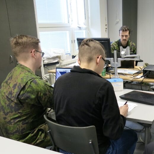 Ryhmä ihmisiä luokkahuoneessa pöydän ääressä.