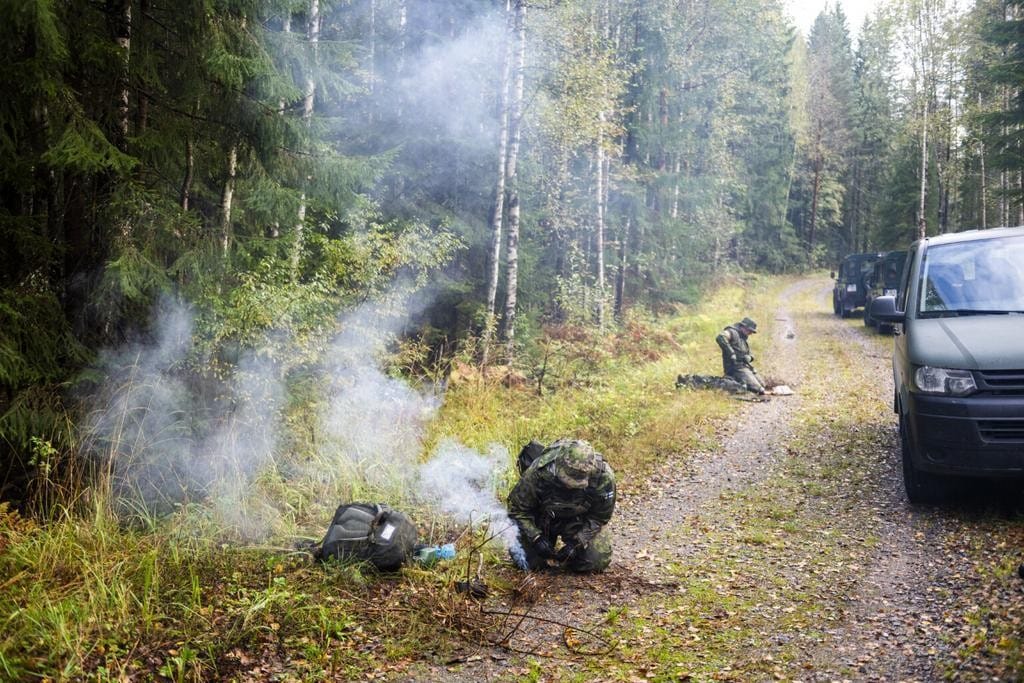 Kaksi sotilasta sytyttävä nuotioita soratiellä.