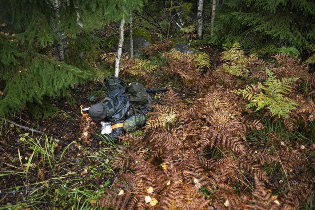 Sotilas maastossa kyykyssä tekemässä nuotiota.