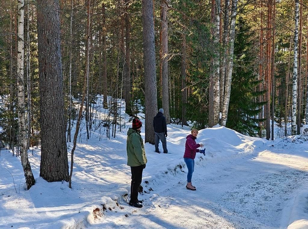 Ihmisiä lumisella metsäpolulla.