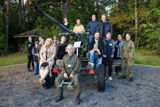 Ryhmäkuva tykin ympärille kokoontuneista ihmisistä, jotka hymyilevät.