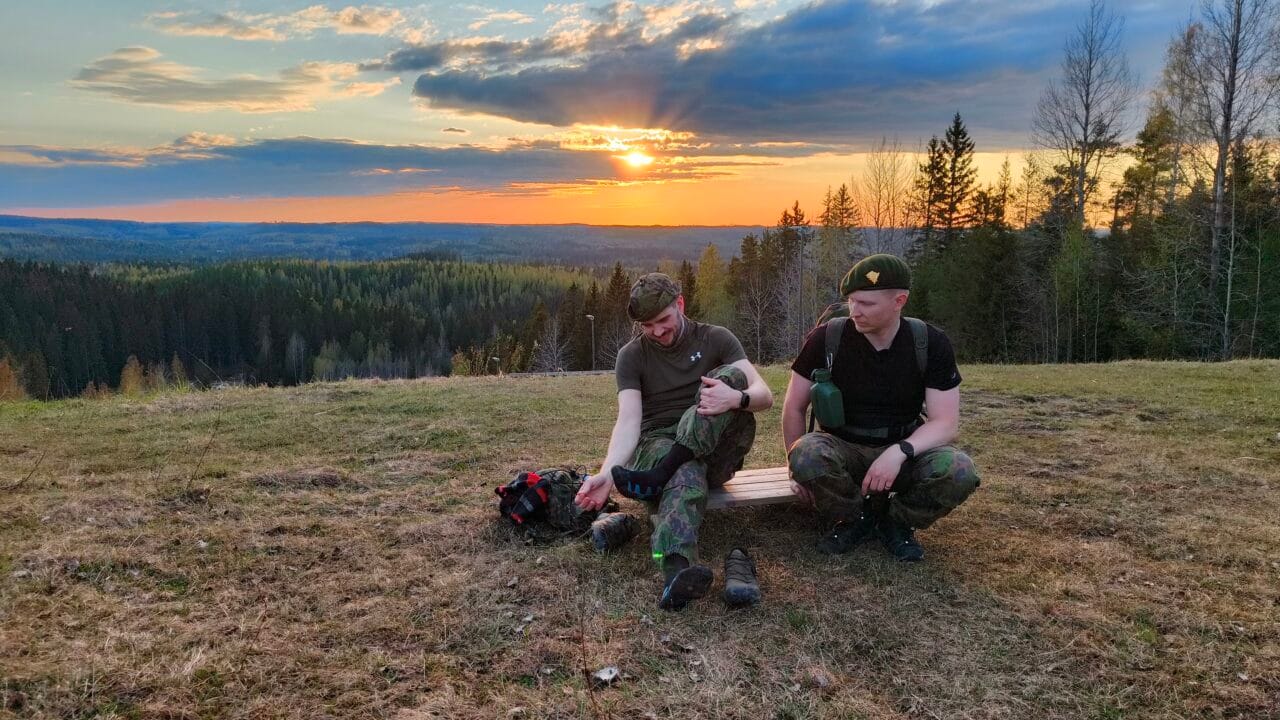 Kaksi henkilöä istuvat maassa kaunis auringonlasku taustallaan