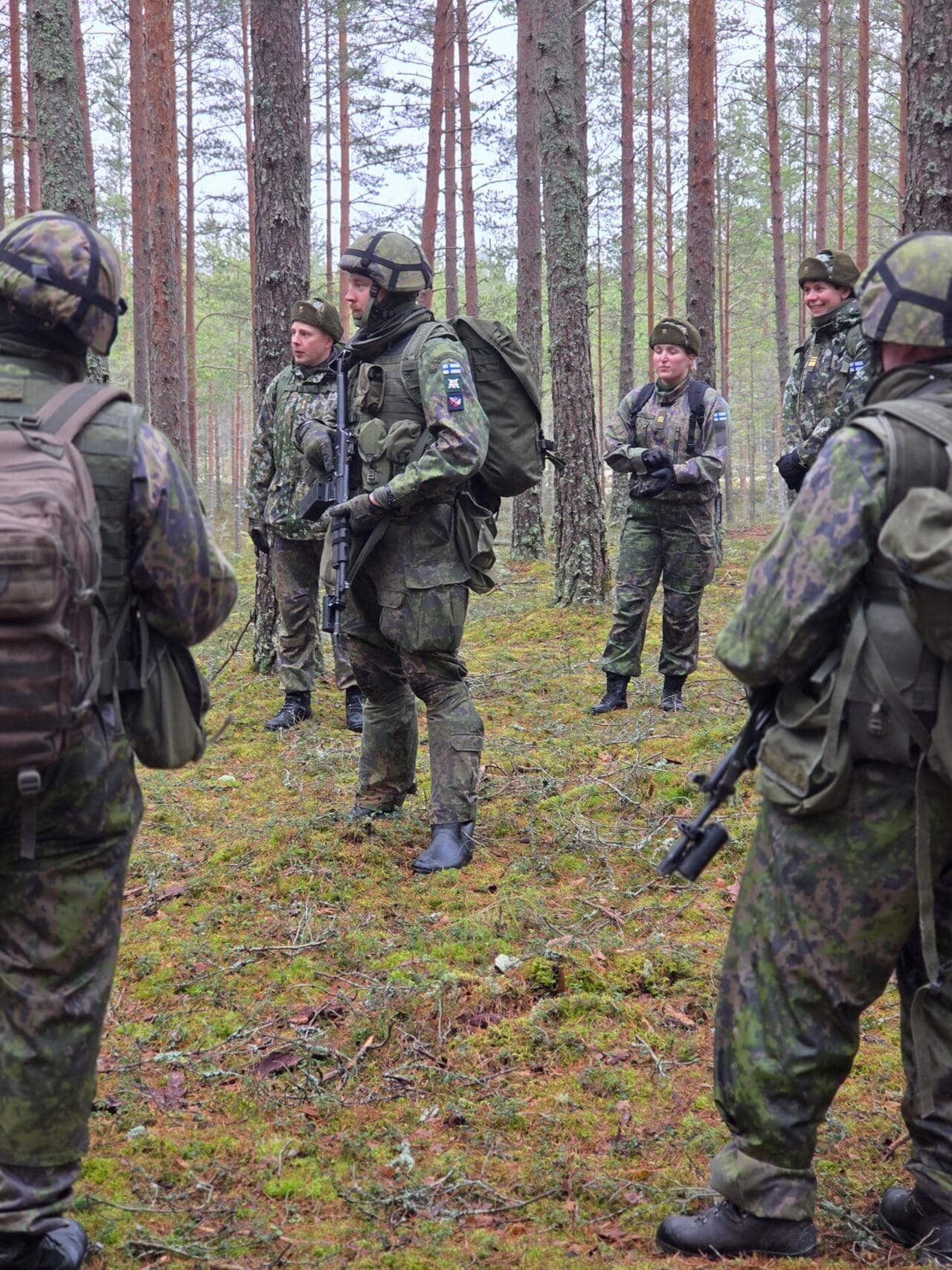 Ryhmä sotilasasuisia henkilöitä metsässä aseet käsissään.