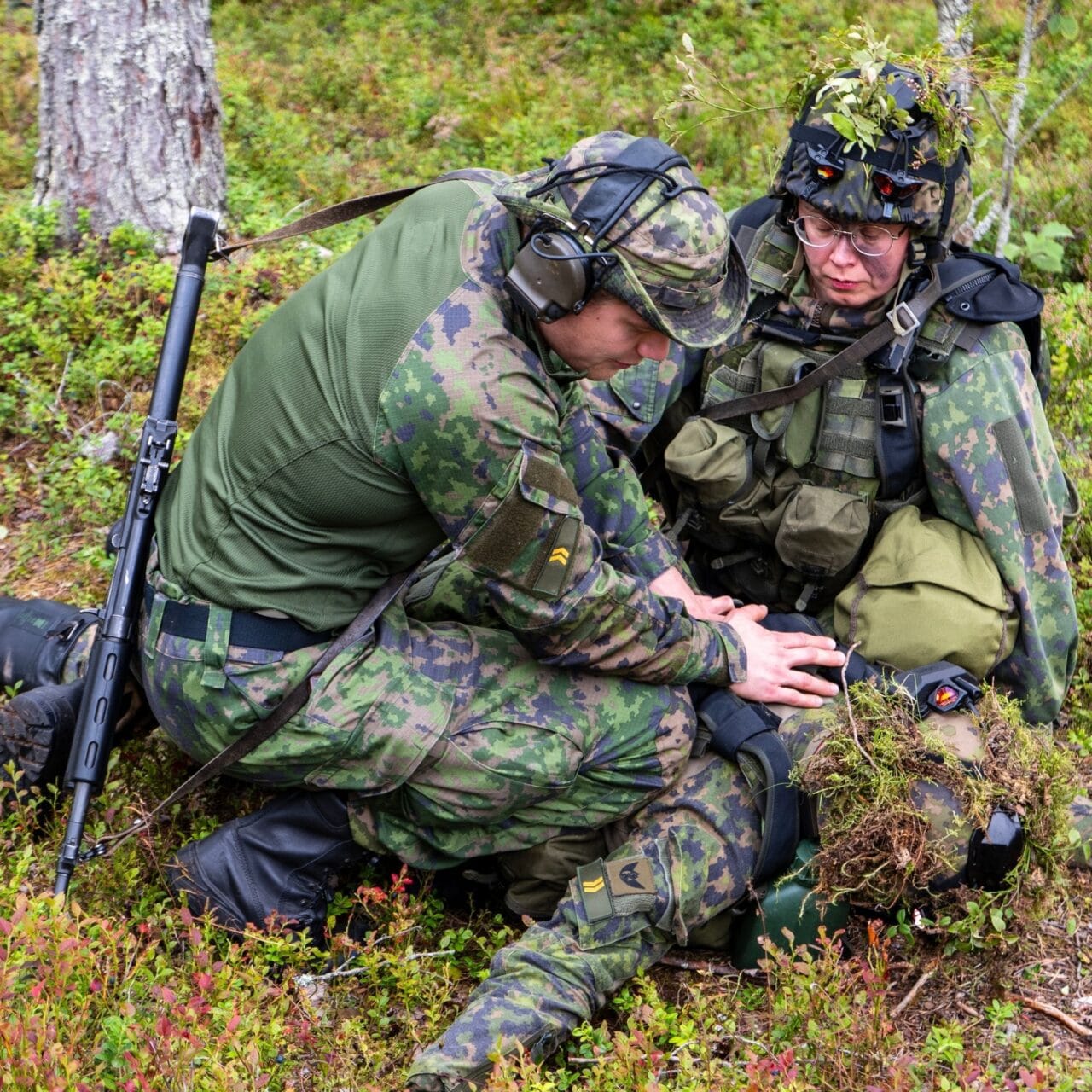 Reserviläiset auttamassa kaveria metsässä jonka toimintakyky on rajoittunut.
