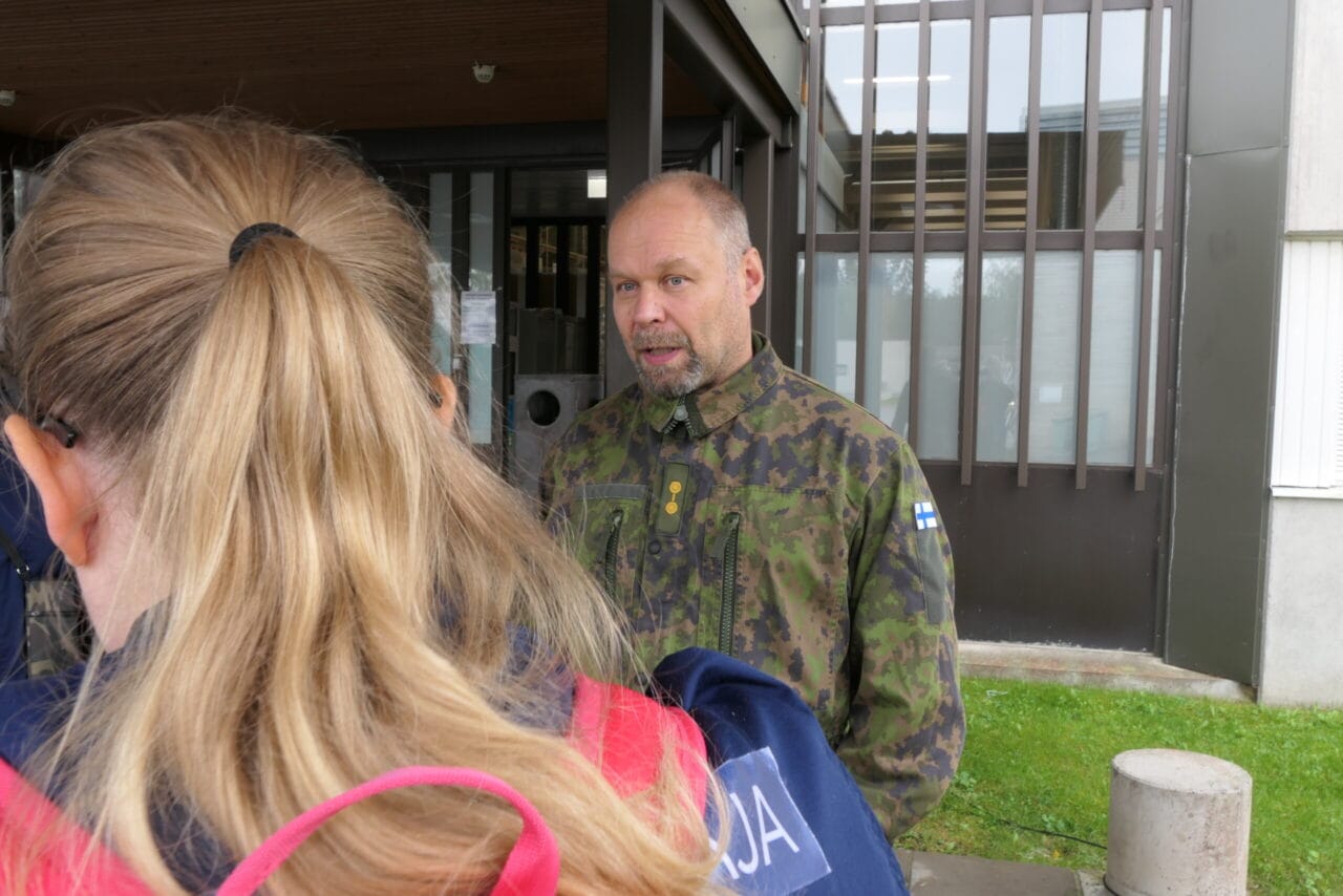 Nainen haastattelee miestä, joka on maastopuvussa
