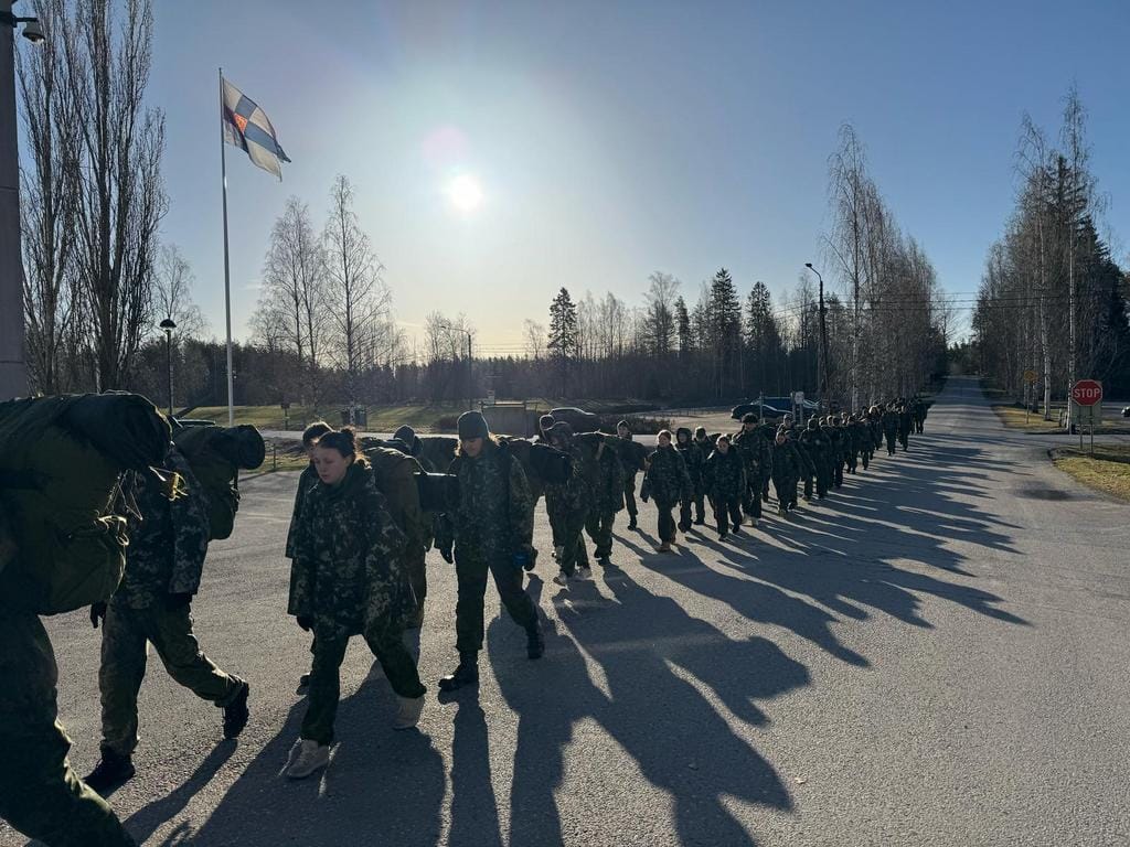 Pitkä jono maastopukuisia nuoria marssimassa tiellä